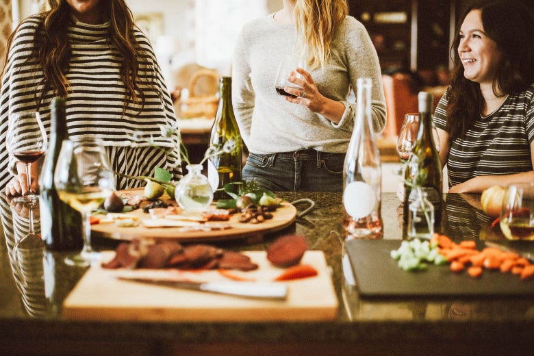 Three women talking in a kitchen at a gathering